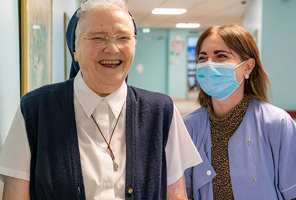Une femme d'église et une aide soignante souriantes.