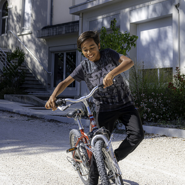 Jeune garçon souriant sur un vélo.