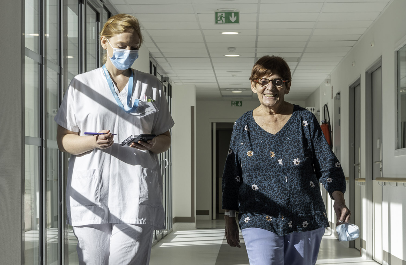 Deux femmes marchant dans un couloir d'hôpital.